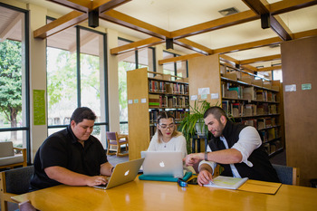 three students studying in the library