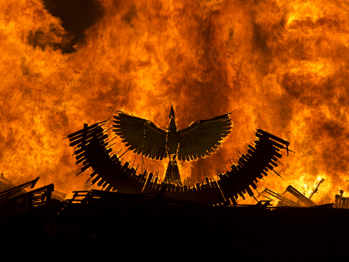 A wooden phoenix rises from the ashes atop of the pit fire.